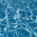 Immagine di una piscina cristallina circondata da piante, senza utilizzo di cloro o sale.